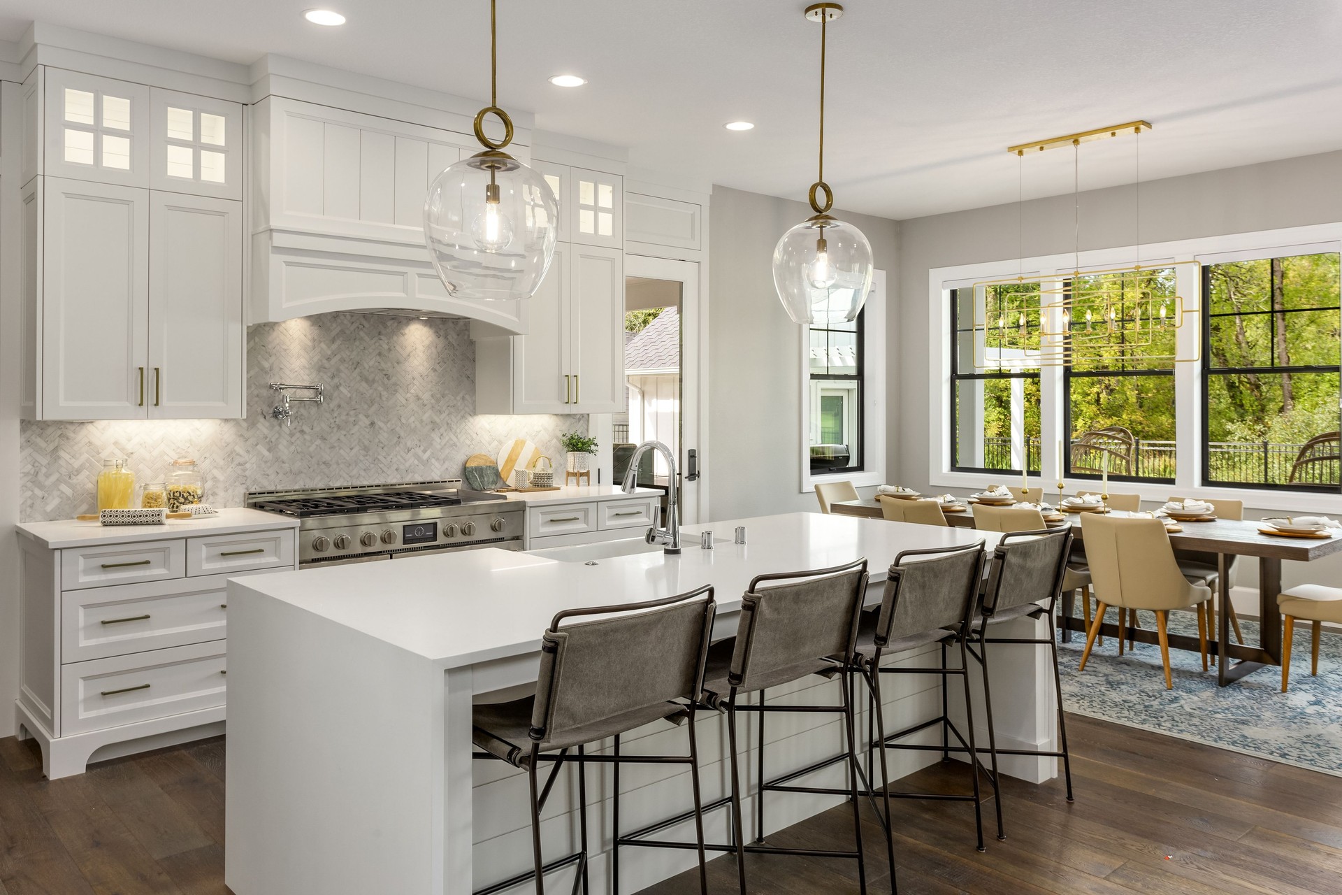 beautiful kitchen in new luxury home with island, pendant lights, and hardwood floors.